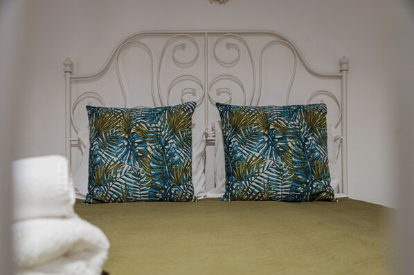 A bed with a white metal frame and two decorative pillows with a leaf pattern. - Casa da Fonte de Cima: O refúgio perfeito em São Miguel! (Açores)