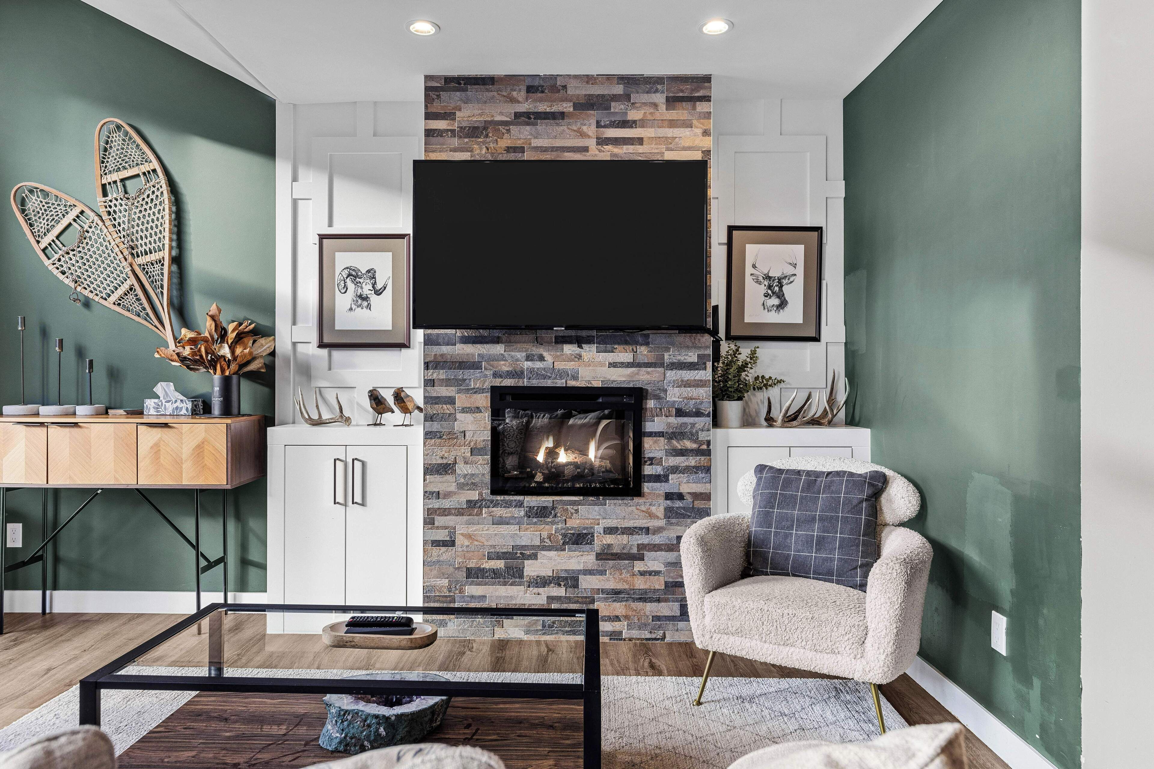 A modern living room with a fireplace, white cabinets, and a mounted TV.