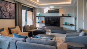 Una sala de estar moderna con un televisor de pantalla plana grande, asientos cómodos y una escultura decorativa de un caballo en la pared.