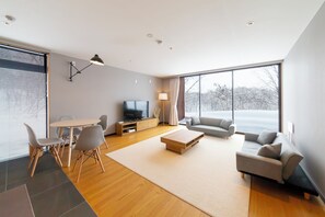 A modern living room with a sofa, coffee table, and TV. - Mori Casa (Kutchan)