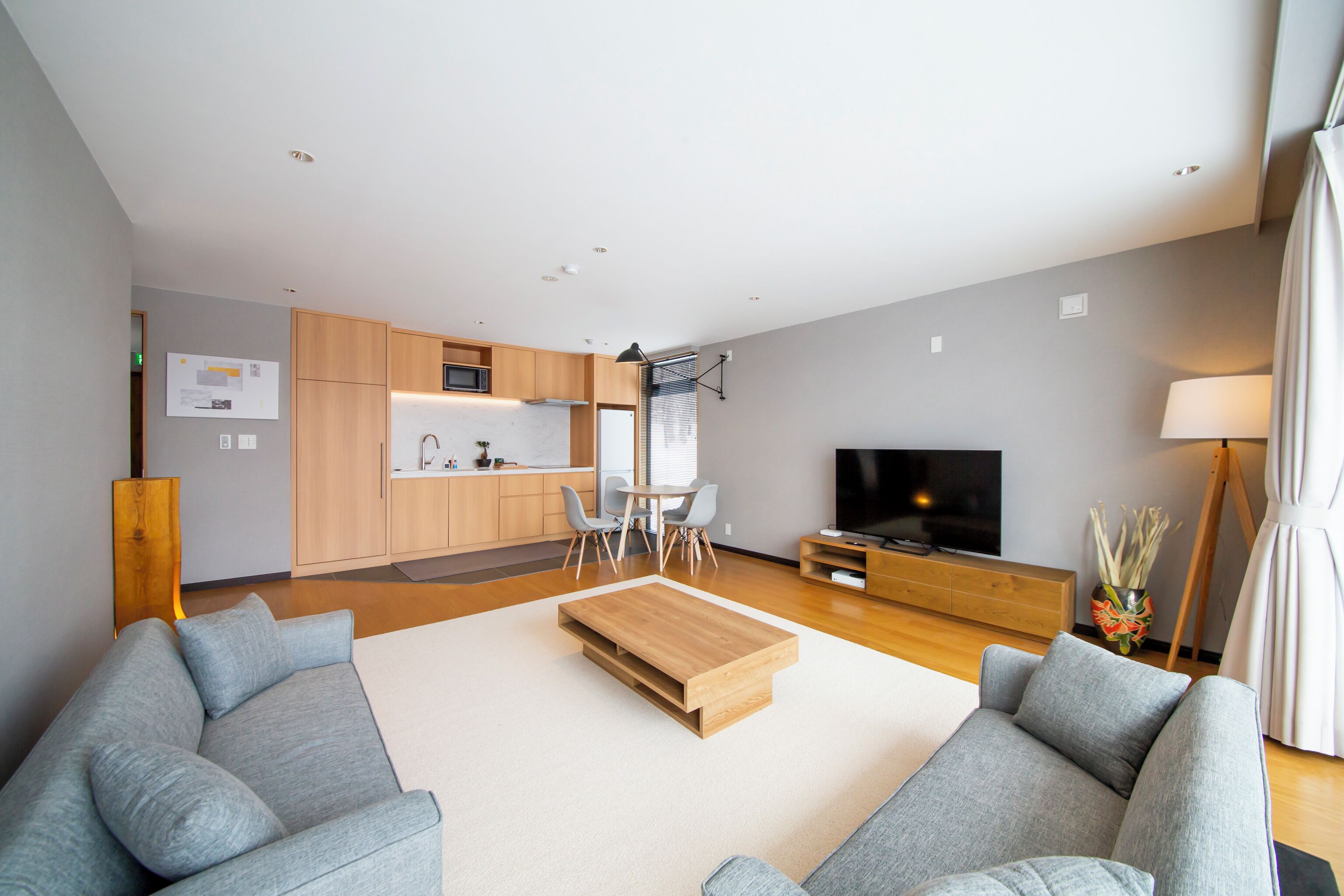 A modern living room with a grey sofa, a wooden coffee table, and a TV.
