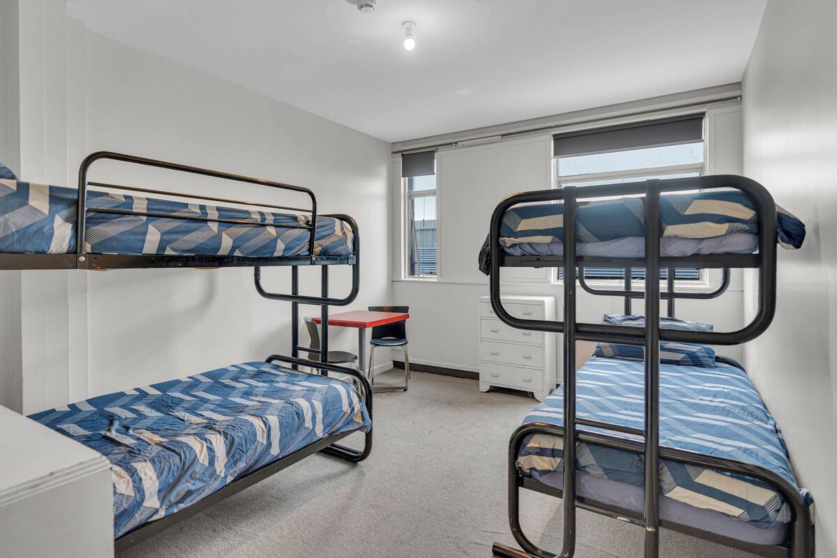 Een slaapzaal met stapelbedden, een bureau en een stoel.