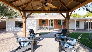 Une terrasse extérieure avec deux chaises longues et un ventilateur de plafond.