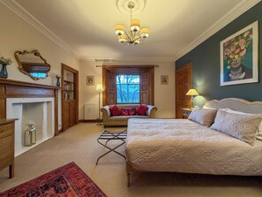 A bedroom with a bed, a fireplace, a window, and a chandelier.