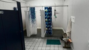 A bathroom with tiled floors, a shower area with patterned curtains, and a towel rack. - Strawberry Crossroads (Pittsville)