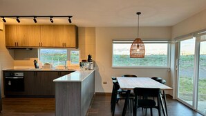 Une cuisine moderne avec des meubles en bois, un îlot central et un coin repas comprenant une table et des chaises.