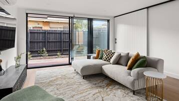 A modern living room with a sectional sofa, a small side table, and a patterned rug.