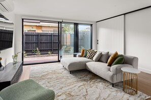 A modern living room with a sectional sofa, a small side table, and a patterned rug. - Sierra Vista Pet Friendly Holiday Home in Rosanna (Rosanna)
