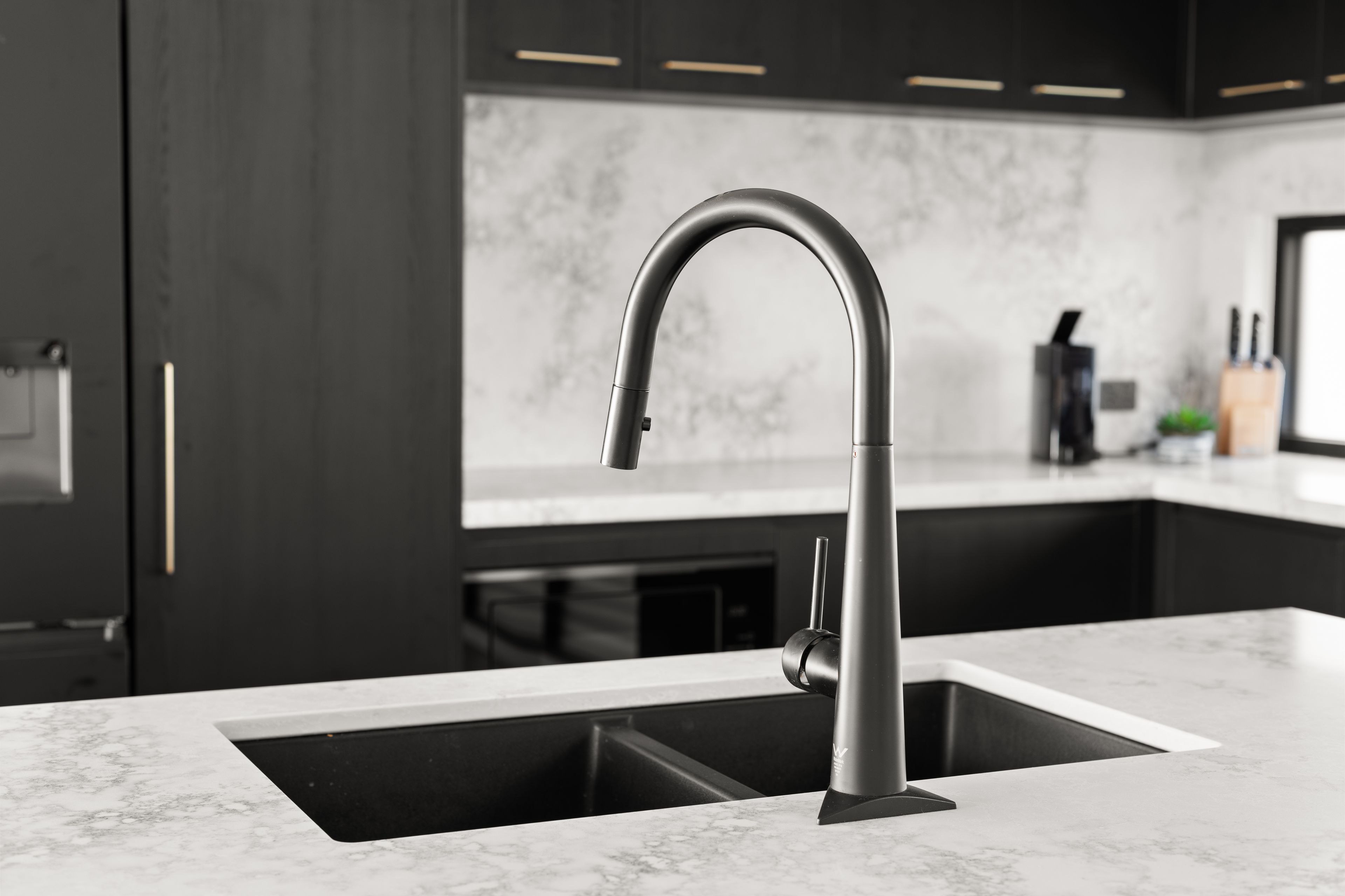 A modern kitchen with a sleek faucet, dark cabinetry, and a marble countertop.