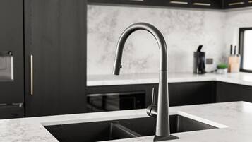 A modern kitchen with a sleek faucet, dark cabinetry, and a marble countertop.