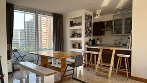 Un apartamento moderno con comedor, cocina y ventanas amplias que ofrecen vistas de la ciudad.