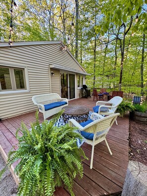 A deck with wicker furniture, a grill, and a covered patio area.