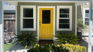A house with a yellow front door, two windows, and a porch with potted plants. - Stylish, Modern 3-Level House-Yard-Patio-Balcony-Sauna- Blocks to Beaches - OB  (San Diego)