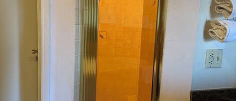 Un bagno con doccia vetro, pareti piastrellate e un piano d'appoggio con asciugamani.