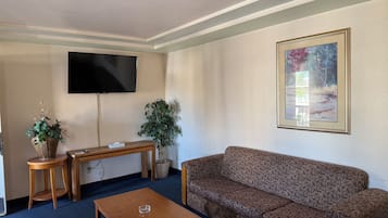 Un salón con sofá, mesa de centro, televisor y un cuadro en la pared.
