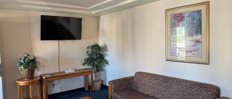 Un soggiorno con divano, tavolino, televisione e un quadro appeso al muro.