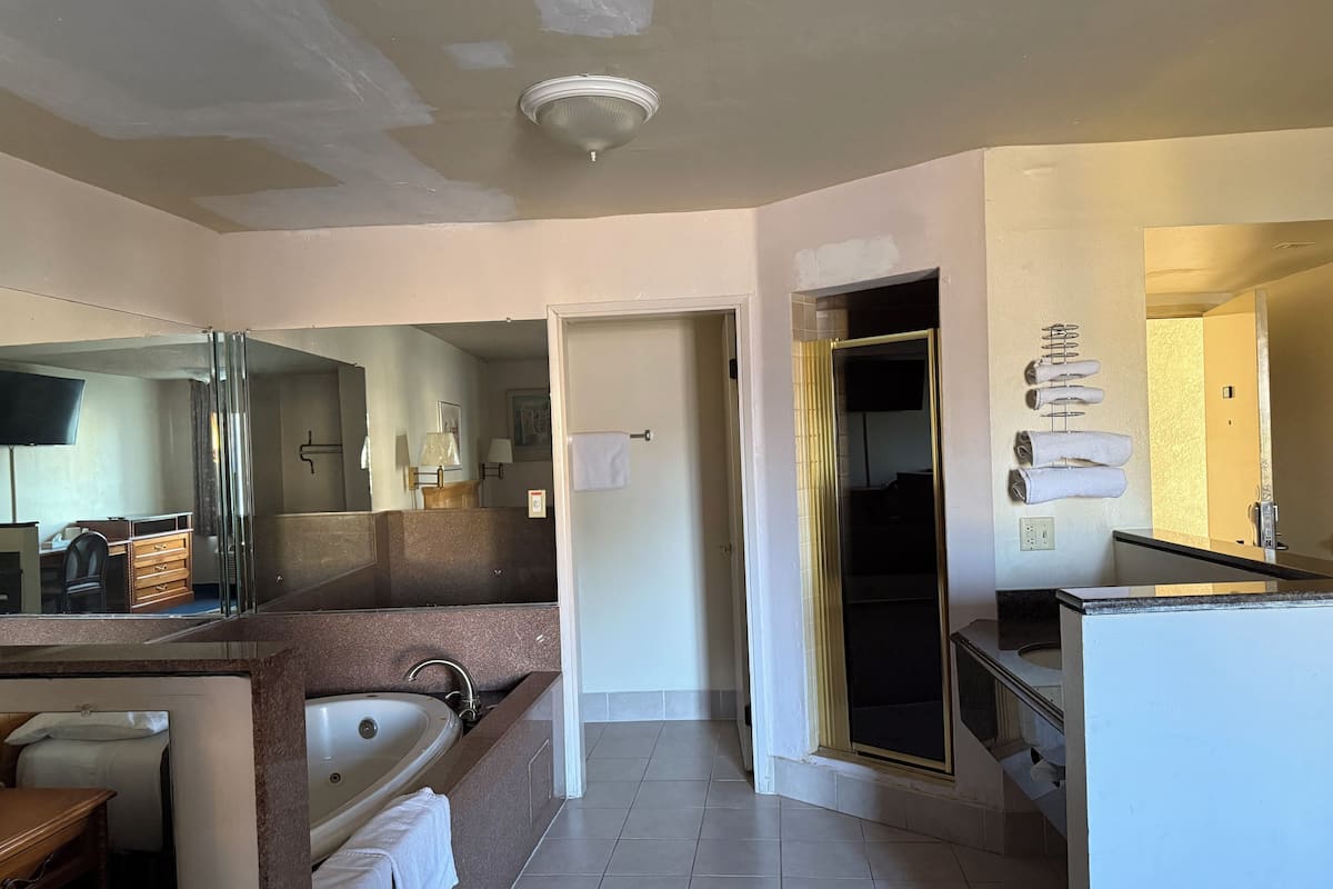 A modern bathroom with a bathtub, sink, and shower area. There is a mirror above the sink and a towel rack on the wall.