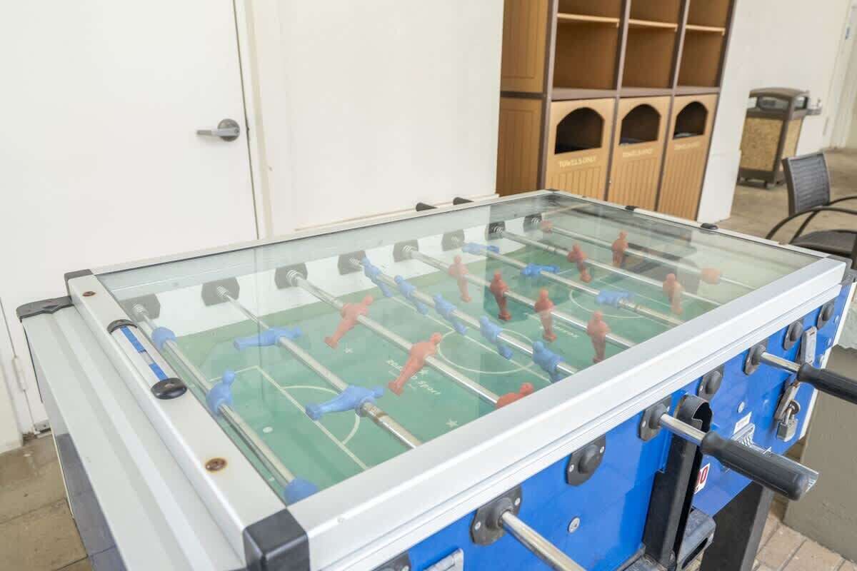 A foosball table in a room with a white door and wooden cabinets.