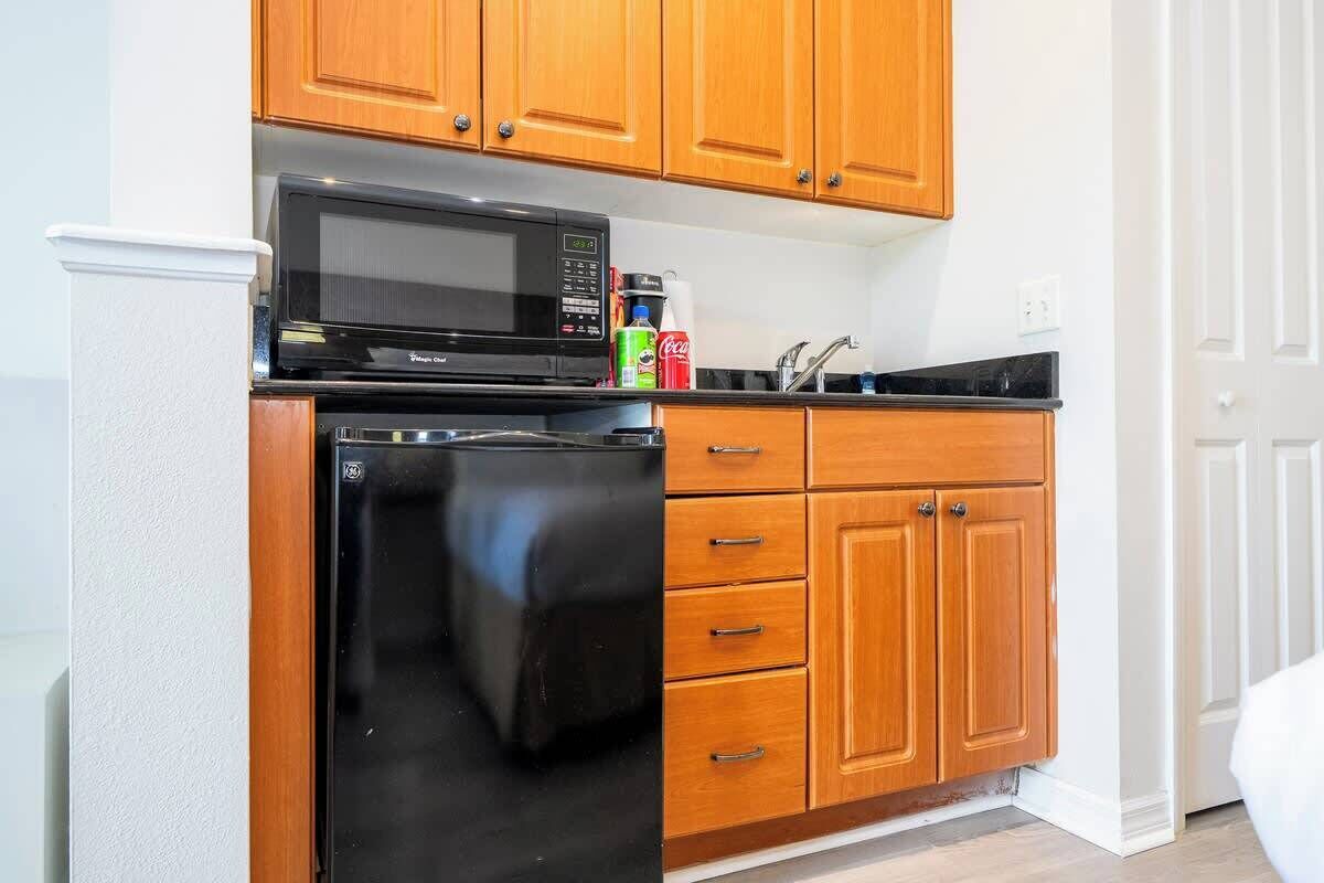 A compact kitchen with wooden cabinets, a microwave, a dishwasher, and a sink.