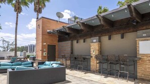Une terrasse extérieure avec des sièges, un espace bar et un mur en briques.