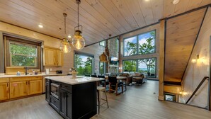 A spacious kitchen with wooden cabinets, a large island, and pendant lighting. - New/Theater/Indoor pool/Hot tub/Fire pit/Arcades/View (Sevierville)