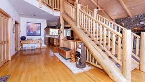 Un interior espacioso con una escalera de madera, una pared de piedra y un cuadro grande.