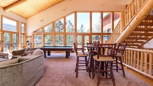 Amplia habitación con mesa de billar, sofá y comedor con sillas de madera.