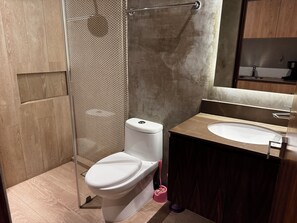 A modern bathroom with a toilet, sink, and shower.