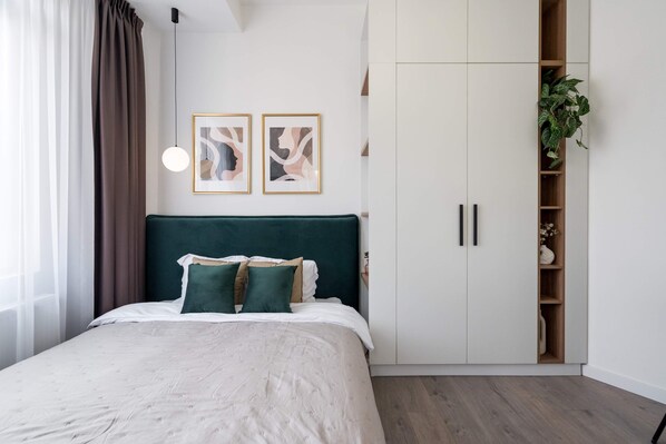 A bedroom with a bed, a wardrobe, and two framed artworks on the wall. - Contemporary Aparthotel 2-BR Flats Near Old Town, Quiet & Serene (Bucharest)