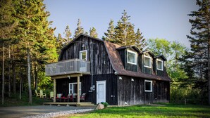 A rustic wooden house with a balcony, surrounded by a forest. - Ultra Private Oceanfront Cottage with Sunset Views (Middleton)