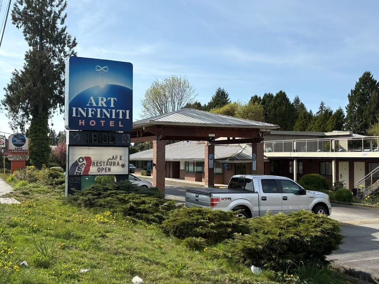 Une enseigne indiquant un hôtel ART INFINITI, avec une enseigne de café et de restaurant à proximité.