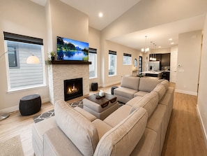 A modern living room with a fireplace, a large flat-screen TV, and a sectional sofa.