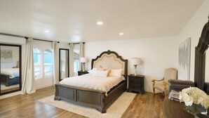 A spacious bedroom with a large bed, a nightstand, a chair, and a mirror. - Spacious 5-bedroom house with a peaceful view in Arroyo Grande (Arroyo Grande)