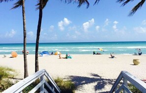 A beach with palm trees, tents, and umbrellas. - Walnut Beach Bungalow (Hollywood)