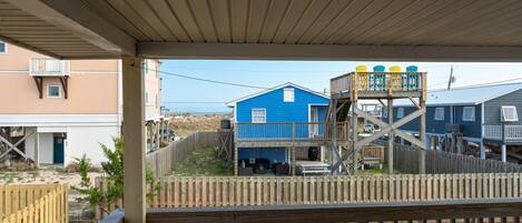 Um deck de madeira com vista para uma casa azul com um deck de madeira e um edifício branco ao fundo.