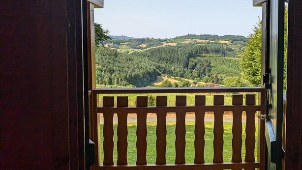 Un balcón de madera con vistas a un paisaje montañoso.