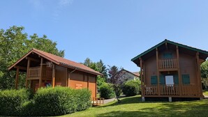 Dos cabañas de madera con balcones, rodeadas de exuberante vegetación.