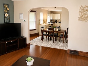 A living room with a TV, a dining area with a table and chairs, and a kitchen visible through an archway. - The Evergreen - Hear the Roar of Niagara Falls - 5 Minutes to Niagara Falls (Niagara Falls)
