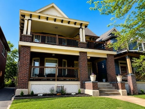 A two-story house with a balcony, a front porch, and a well-maintained lawn.