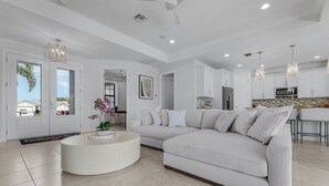 A modern living room with a grey sofa, a white coffee table, and a chandelier.