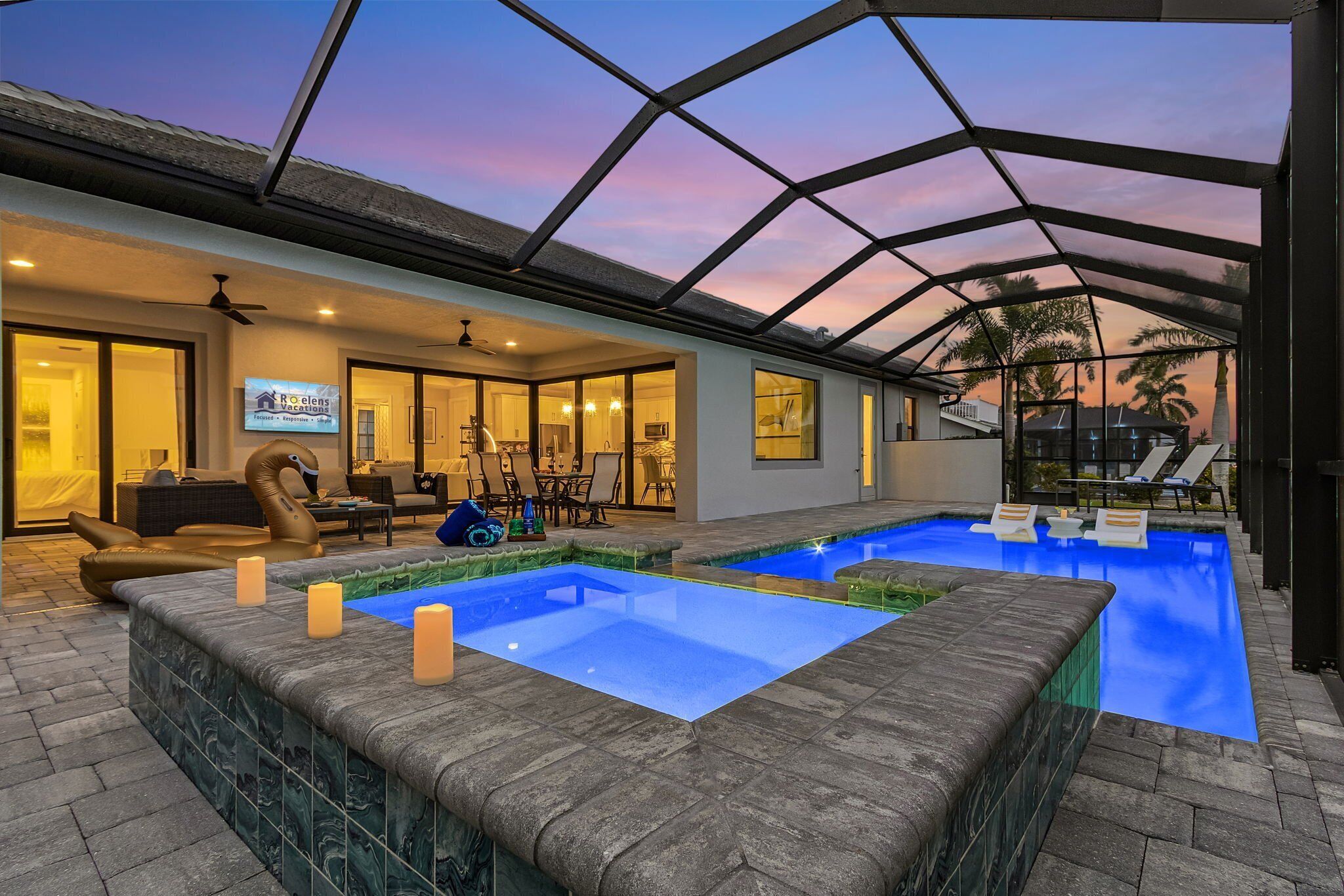 Uma área de piscina interior luxuosa, com teto de vidro, duas banheiras de hidromassagem e um espaço de estar com televisão.