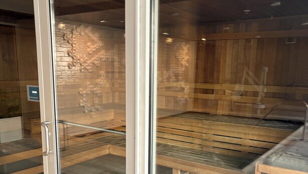 A sauna room with wooden benches and a glass door. - Cozy Luxury Unit Convenient location (Decatur)