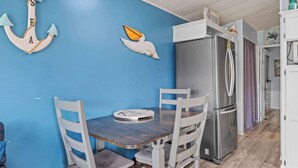 A kitchen with a blue wall, white cabinets, a stainless steel refrigerator, and a wooden table with chairs.