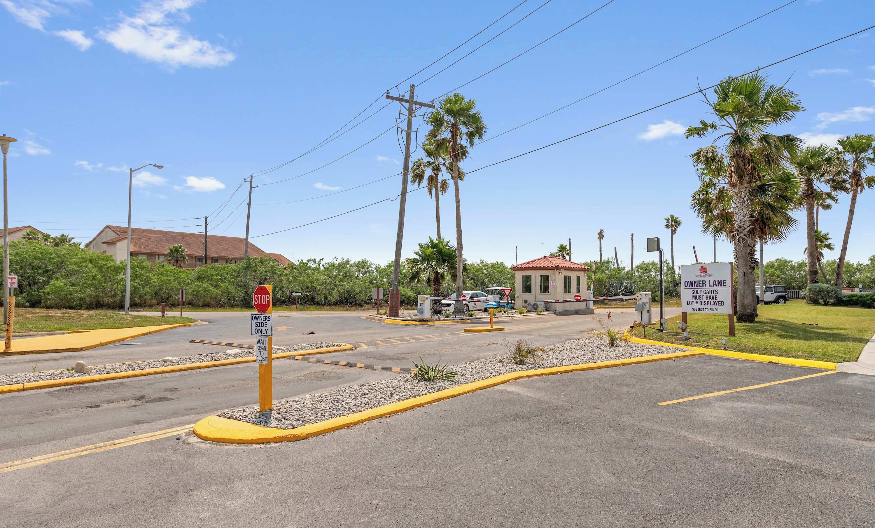 Una entrada con portón, una señal de stop, una borda amarilla y un cartel que indica acceso para propietarios.