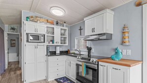A compact kitchen with white cabinetry, a stainless steel oven, and a microwave.