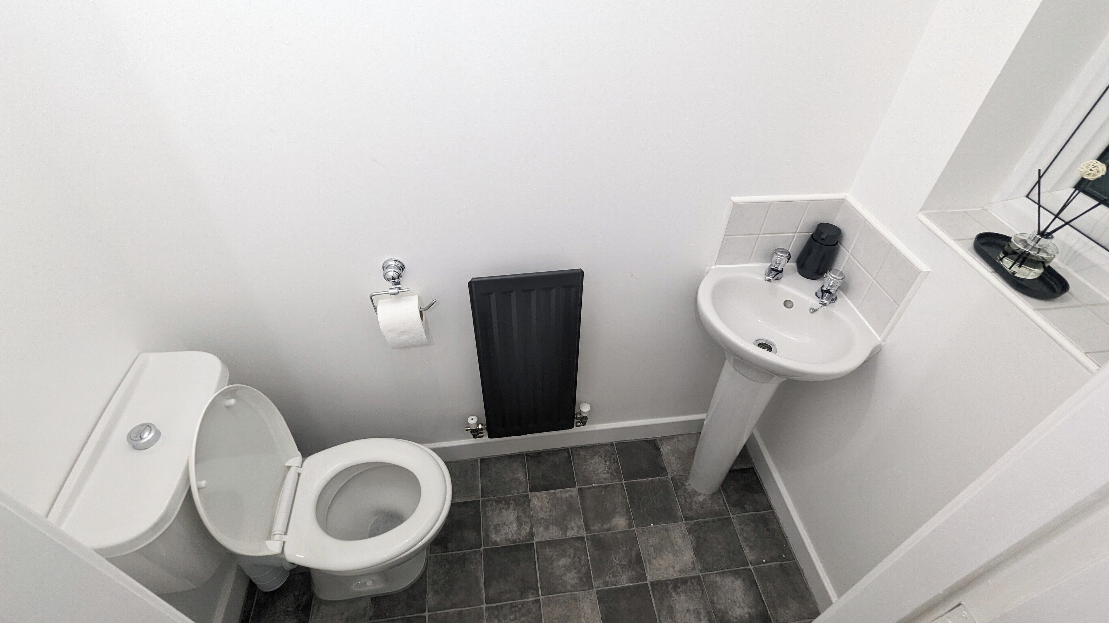 Ein kleines, kompaktes Badezimmer mit Toilette, Waschbecken und Handtuchheizkörper.