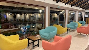 A lobby with colorful chairs, a glass pool, and a tiled floor. - Hosteria & Spa Surillal (San Miguel de Salcedo)