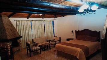 Una habitación acogedora con una cama, una mesa de madera, un sofá y una chimenea.