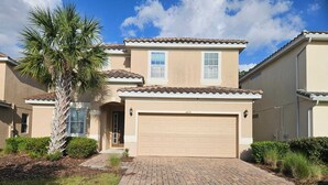 A two-story house with a beige exterior, a tiled roof, and a garage. - Steps away from Resort Pool, Kids Water Park, Hot tub and Gym (Kissimmee)