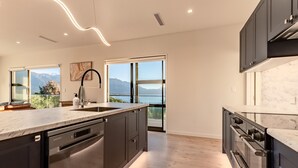 Una cocina moderna con una isla grande, electrodomésticos integrados y vistas a montañas a través de amplios ventanales.